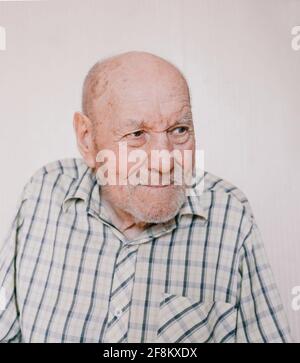 un retrato grande de un anciano sobre un fondo claro con arrugas profundas, manchas de edad. Foto de stock