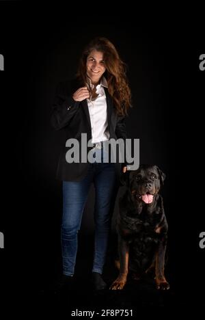 purebred rottweiler y mujer delante de fondo negro