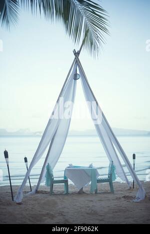 Mesa y sillas bajo un romántico árbol de tela en la playa, Koh Yao, Phang Nga, Tailandia Foto de stock