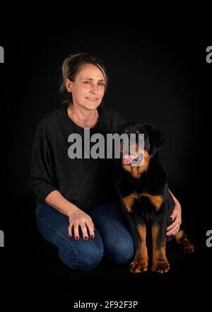 purebred rottweiler y mujer delante de fondo negro