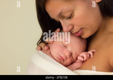 Joven madre de raza mixta posando con sus 7 días bebé recién nacido en primer plano