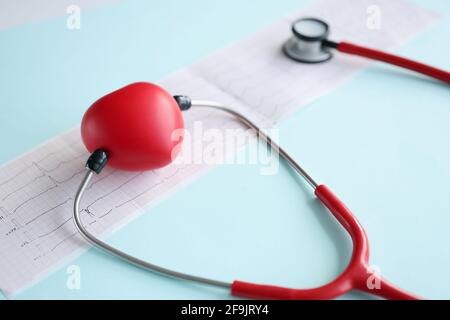 Corazón de juguete rojo y estetoscopio acostado en el primer plano del cardiograma
