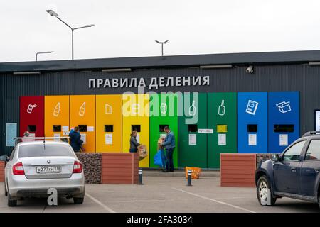 Gran estación de eliminación de residuos separada con marcas de color cerca del aparcamiento con gente depositando basura en San Petersburgo, Rusia Foto de stock