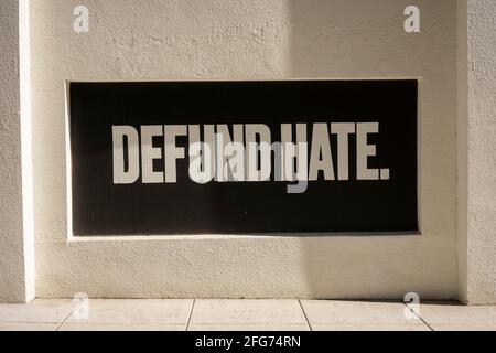 Defund. Hate. Un eslogan positivo pintado en una ventana integrada durante las protestas. Foto de stock