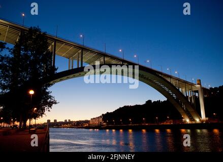 Puesta de sol en el moderno puente Arrabida (Ponte da Arrábida), cruzando el río Duero en Porto, Portugal. Foto de stock