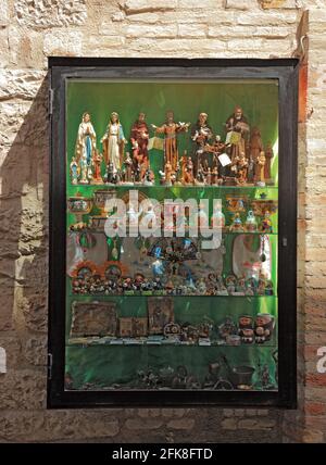 Schaufenster mit Heiligenfiguren, Devotionalien, In der Altstadt von Assisi, Umbrien, Italien Foto de stock