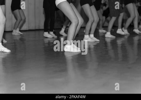 piernas de pequeños bailarines bailando en el escenario en fila, monocromo Foto de stock