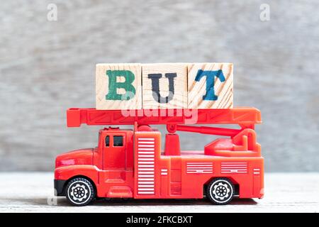 Camión de bomberos rojo mantener el bloque de letras en la palabra pero encendido fondo de madera Foto de stock