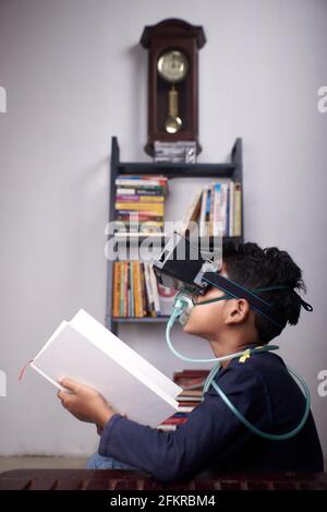 Niño pequeño usando el auricular VR y la máscara del nebulizador estudiando a. cuarentena domiciliaria