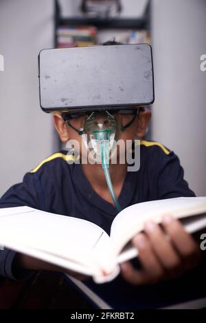 Niño pequeño usando el auricular VR y la máscara del nebulizador estudiando a. cuarentena domiciliaria