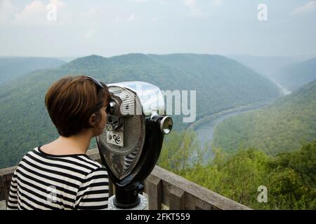 Mujer adulta mediana mirando a través de binoculares operados con monedas, vista trasera, New River Gorge National River, Fayetteville, West Virginia, Estados Unidos Foto de stock