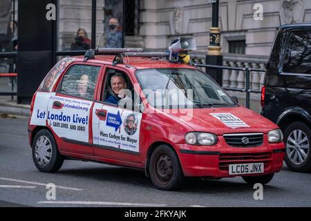 Londres, Reino Unido. 4th de mayo de 2021. Piers Corbyn 'Battle Bus' continúa sus rondas de Westminster. La activista Heiko Khoo conduce en círculos alrededor del centro de Londres con carteles que muestran 'Vote Corbyn' y 'Let London Live' cubriendo los lados de un coche rojo con un megáfono atado a la cima. Piers Corbyn, candidato del alcalde londinense, planea poner fin a las «reglas covid con» y revertir el tratamiento discriminatorio contra quienes se niegan a usar una máscara. Crédito: Guy Corbishley/Alamy Live News Foto de stock