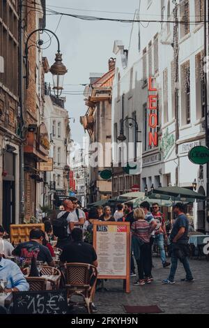 Bruselas, Bélgica - 16 de agosto de 2019: Personas que pasan por los restaurantes en una calle estrecha de Bruselas, la capital de Bélgica y una ciudad popular bre