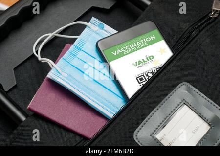 Concepto de certificado de vacunación internacional: Una maleta con pasaporte, una máscara quirúrgica y un teléfono inteligente que muestre una vacunación internacional válida