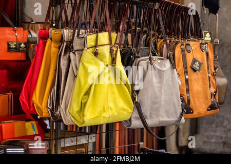 Muchos bolsos de cuero bolsos colores vivos coloridos que cuelgan en la exhibición en el mercado de la calle de compras en Florencia, Florencia, Toscana, Italia Foto de stock