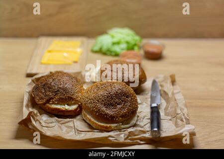 Pan de hamburguesa, lechuga y queso en la mesa. Proceso de cocción de hamburguesas hechas en casa.