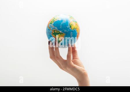 Globo en la punta de los dedos de la mujer. Mano hembra sujeta el globo. Mundo en manos humanas. Fondo blanco. Foto de stock