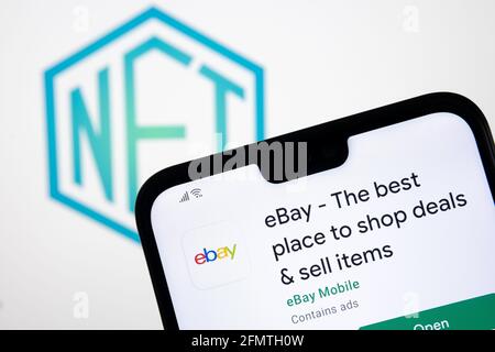 Concepto EBAY NFT. Aplicación eBay vista en el smartphone y logotipo de ficha no fungible borroso en la pantalla de fondo borroso del portátil. Stafford, Reino Unido Foto de stock