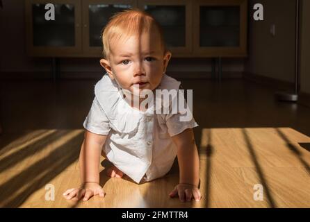 Hermoso bebé de 1-2 años arrastrándose en la sala de estar en casa.