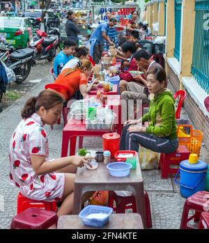 Las familias vietnamitas comen comida callejera en el café de pavimento - sólo 1 personas en foco tiro con abertura f/3,5 usando profundidad de campo poco profunda, Da Nang, Vietnam