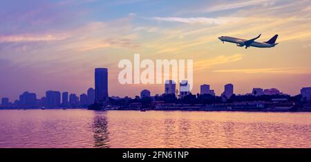 Avión de pasajeros en cielo nublado sobre el río Nilo al atardecer en El Cairo, vista panorámica.