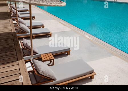 Hamacas de madera con sombrillas ratang cerca de la piscina Fotografía de  stock - Alamy