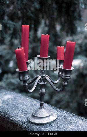 el candelabro de peltre con cinco velas rojas está parado en el hielo afuera en invierno Foto de stock