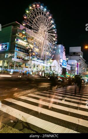 Los peatones aparecen como fantasmas en el cruce en frente de la Noria del Sunshine Sakae edificio en el centro de Nagoya, uno de los más grande del Japón ci Foto de stock