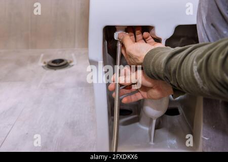Trabajador de la construcción instalando un nuevo bidet blanco en un cuarto de baño Foto de stock