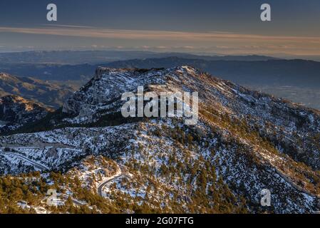 Amanecer visto desde Mont Caro con vistas al macizo de Ports, nevado en invierno (Parque Natural de Els Ports, Tarragona, Cataluña, España) Foto de stock