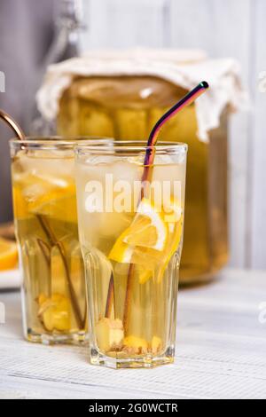 Té kombucha fermentado en casa con limón y jengibre. Vasos de limonada de verano sobre mesa de madera Foto de stock