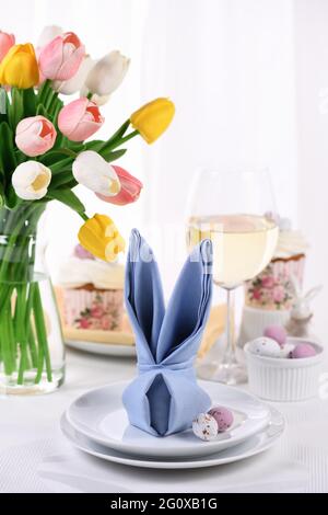 Una servilleta doblada en forma de liebre (conejo), el concepto de fijar una mesa festiva en honor de Pascua. Foto de stock