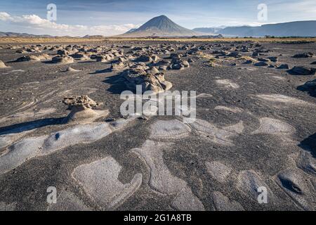 Mudflats cerca del lago Natron con el volcán Ol Doinyo Lengai en el fondo; Tanzania Foto de stock