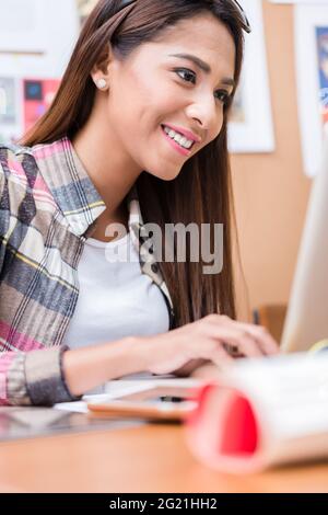 Retrato de una joven mujer asiática motivada sonriendo mientras trabajaba con un portátil en la oficina Foto de stock