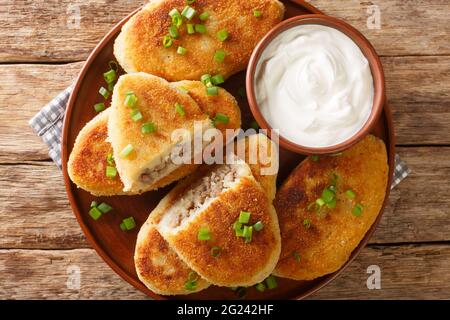 Panqueques de patata Zrazy con relleno de carne con crema agria primer plano en un plato sobre la mesa. Vista horizontal de arriba Foto de stock