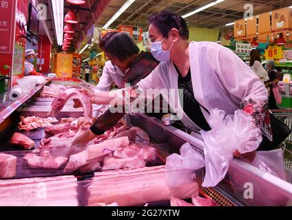 Fuyang, China. 09th de junio de 2021. Los compradores compran carne fresca en el supermercado RT Mart.El índice de precios al consumidor de China, un indicador principal de la inflación, creció un 1,3 por ciento año con año el mes pasado, frente al 0,9 por ciento registrado en abril, informó el miércoles la Oficina Nacional de Estadísticas. La lectura del IPC repuntó a medida que los precios de los alimentos subieron en medio de una oferta ajustada de pescado y huevos de agua dulce, mientras que los precios no alimentarios aumentaron con los costos de transporte elevados por los crecientes precios internacionales del petróleo crudo, indicó el NBS. Crédito: SOPA Images Limited/Alamy Live News Foto de stock