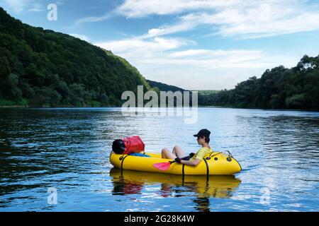 Turista en barco de goma de packraft amarillo con el padle rojo en un río del amanecer. Rafting. Concepto vital activo Foto de stock