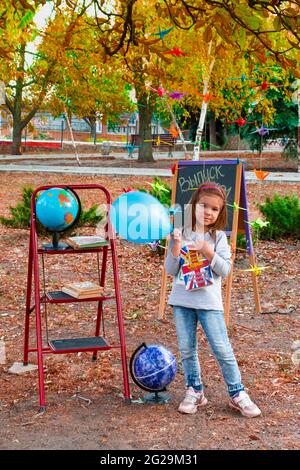 Lisichansk. Ucrania 04.10.2020 Pequeña escuela con un globo azul contra el fondo de un parque otoñal contra el fondo de una junta escolar Foto de stock