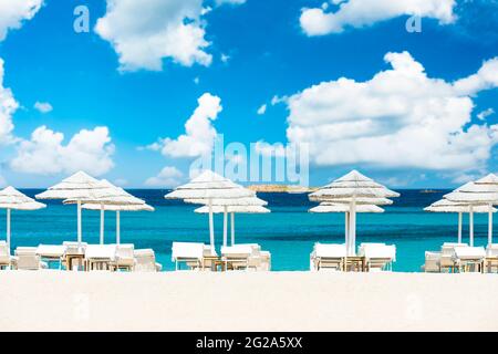 (Enfoque selectivo) Vistas impresionantes de algunas sombrillas blancas y hamacas en una playa de arena blanca bañada por un hermoso mar turquesa. Foto de stock