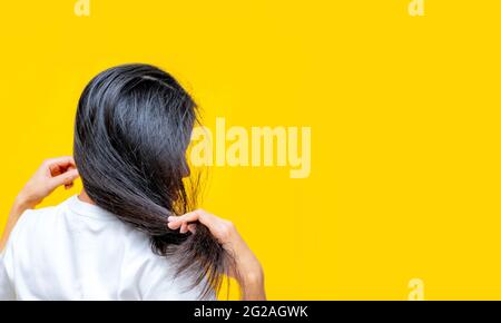 Vista posterior de una mujer asiática que sostiene el cabello dañado sobre  fondo amarillo. Pérdida de cabello y problema de cabello delgado en la  mujer. Cabello largo negro seco y quebradizo Fotografía de stock - Alamy