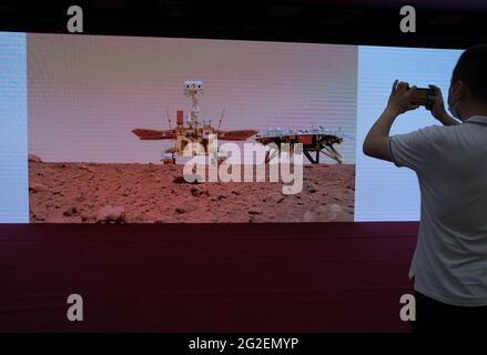 (210611) -- BEIJING, 11 de junio de 2021 (Xinhua) -- Un miembro del personal toma fotos en la ceremonia durante la cual se desvelan nuevas imágenes tomadas por el primer rover chino de Marte Zhurong en Beijing, capital de China, el 11 de junio de 2021. La Administración Nacional del Espacio de China (CNSA) publicó el viernes nuevas imágenes tomadas por el primer rover de Marte del país, Zhurong, mostrando la bandera nacional en el planeta rojo. Las imágenes fueron reveladas en una ceremonia en Beijing, lo que significa el éxito total de la primera misión de exploración de Marte de China. Las imágenes incluyen el panorama del sitio de aterrizaje, paisaje marciano y una selfie del ro Foto de stock