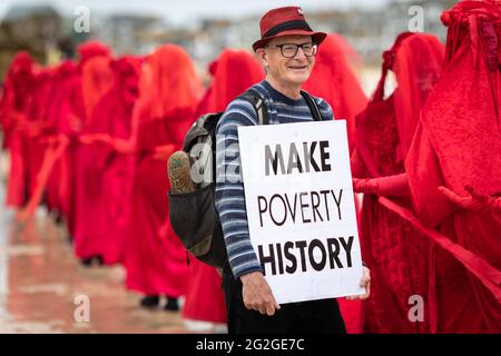 St Ives, Reino Unido. 11th de junio de 2021. Un hombre con un cartel hace una pausa para dejar pasar el movimiento XR durante una marcha contra el G7. El movimiento de la Rebelión de Extinción desciende a la pequeña ciudad costera de Cornualles. Cientos de manifestantes marchan por la aldea cerca de donde los delegados se reúnen para el 47th G7. En el evento, los líderes mundiales se reúnen para discutir asuntos relacionados con el cambio climático. Crédito: SOPA Images Limited/Alamy Live News