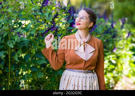 Mujer intelectual joven vestida en 1940s Ropa en un jardín Foto de stock