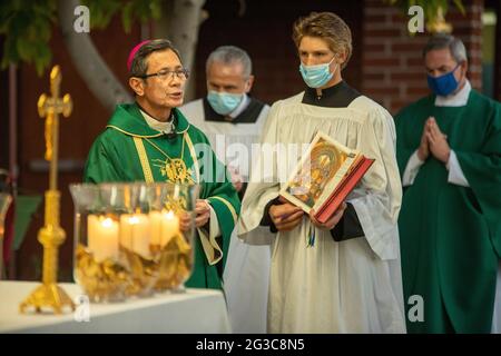 Un sacerdote asiático-americano lee de una Biblia en una misa para reconocer a los miembros de la Vida Consagrada y a los jubilares en una iglesia católica de California. Foto de stock
