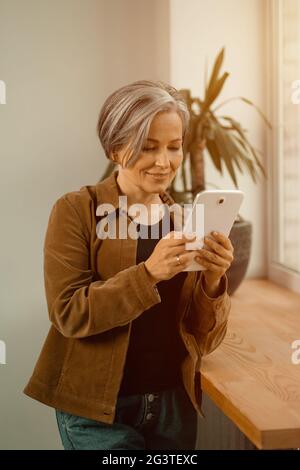 Mujer madura hermosa de pelo gris que tiene videollamada usando la tableta digital. La mujer del negocio freelancer está negociando vía li video