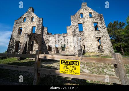 La señal de precaución y la valla impiden que los visitantes del parque se acerquen demasiado a las ruinas abandonadas del castillo en el Parque Estatal Ha Tonka, Missouri Foto de stock