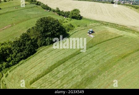 drone tiro de tractor azul con cortacésped cortando prado verde fresco en alguna parte en austria Foto de stock