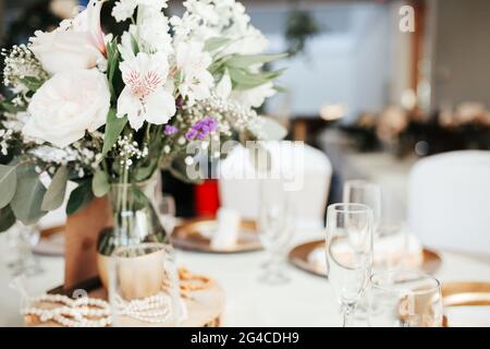 Decoración moderna para bodas - mesas de invitados con manteles blancos,  platos dorados, rosas blancas y arreglos florales de hojas de eucalipto  Fotografía de stock - Alamy