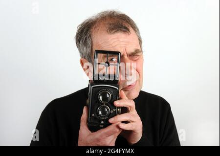 Hombre fotógrafo masculino utilizando una cámara réflex de doble lente Rolleiflex 1930s. Cámara réflex de doble lente Rolleiflex 6x6 K2 estándar fabricada en 1932 Foto de stock