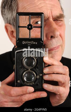 Hombre fotógrafo masculino utilizando una cámara réflex de doble lente Rolleiflex 1930s. Cámara réflex de doble lente Rolleiflex 6x6 K2 estándar fabricada en 1932 Foto de stock